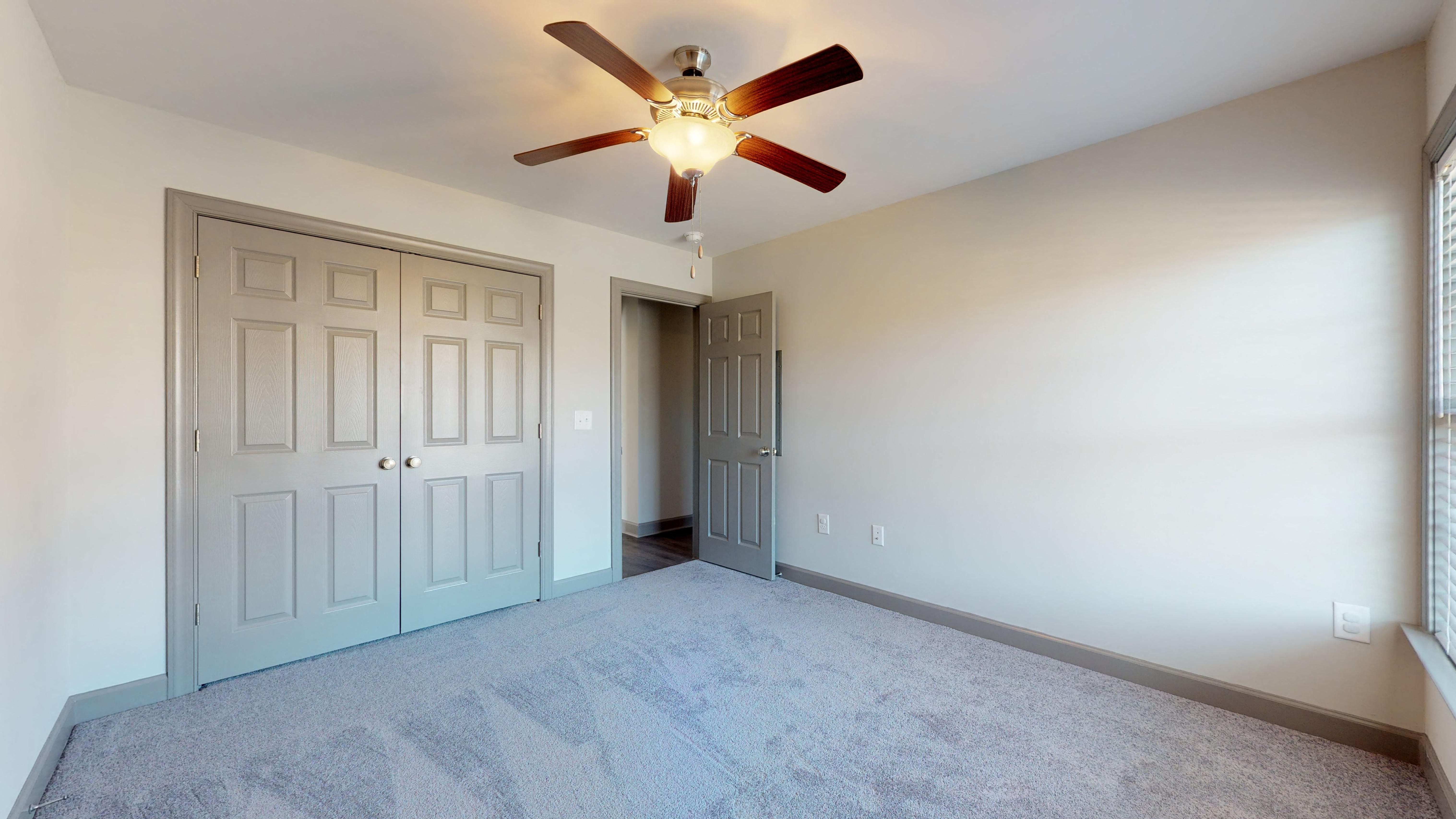 an empty room with a ceiling fan and a door