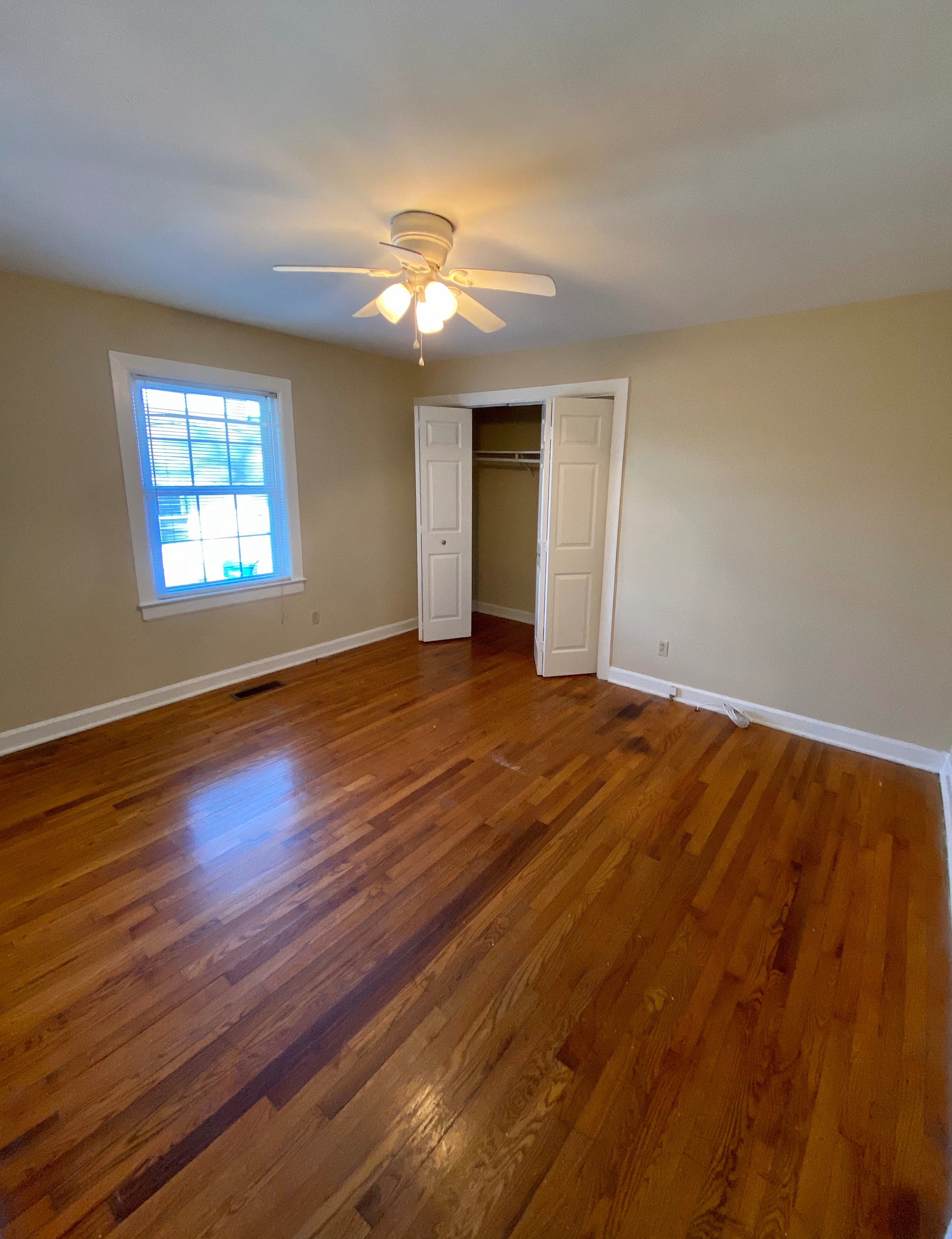 an empty living room with wooden floors and a ceiling fan