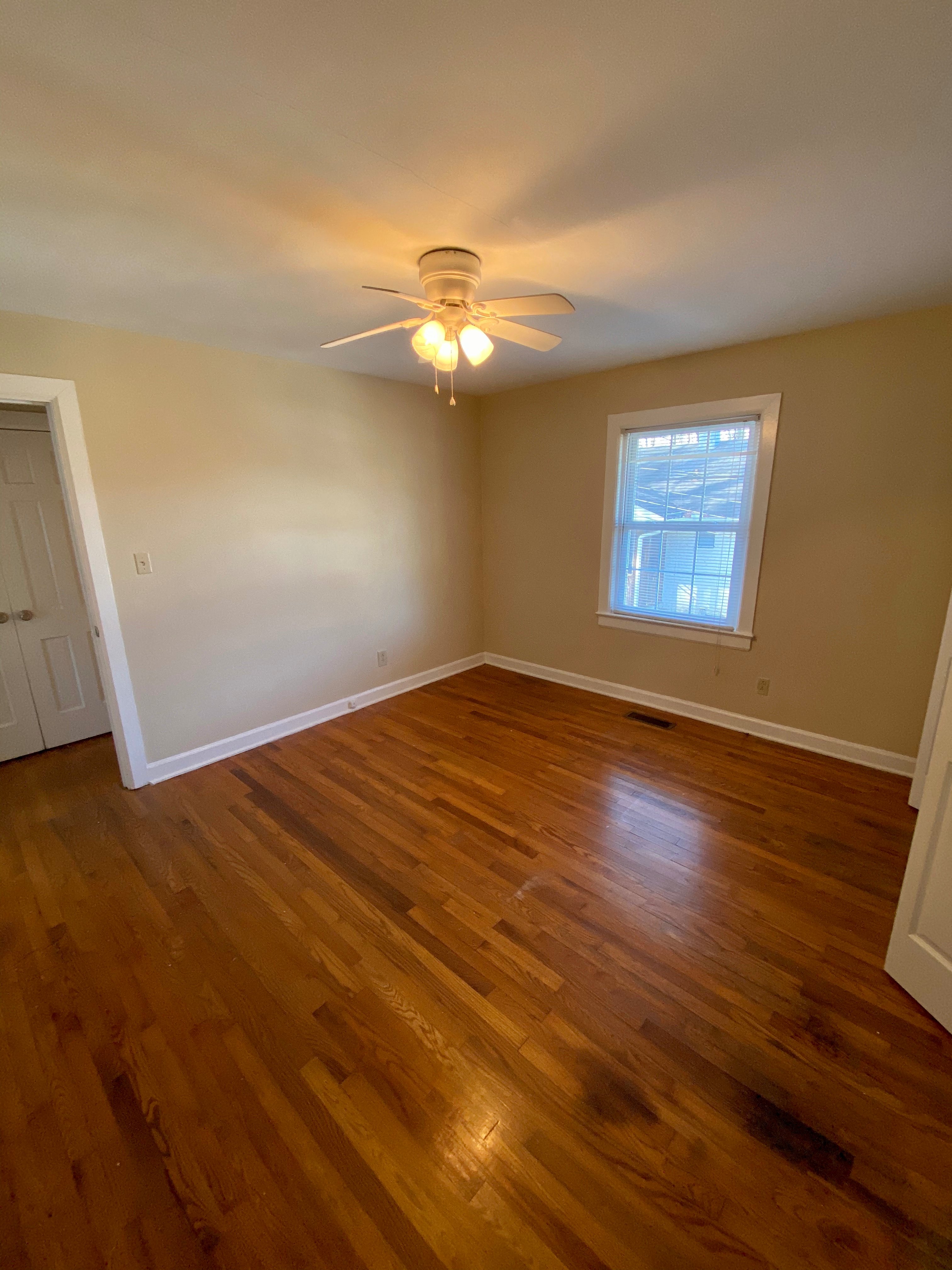 an empty living room with wooden floors and a ceiling fan