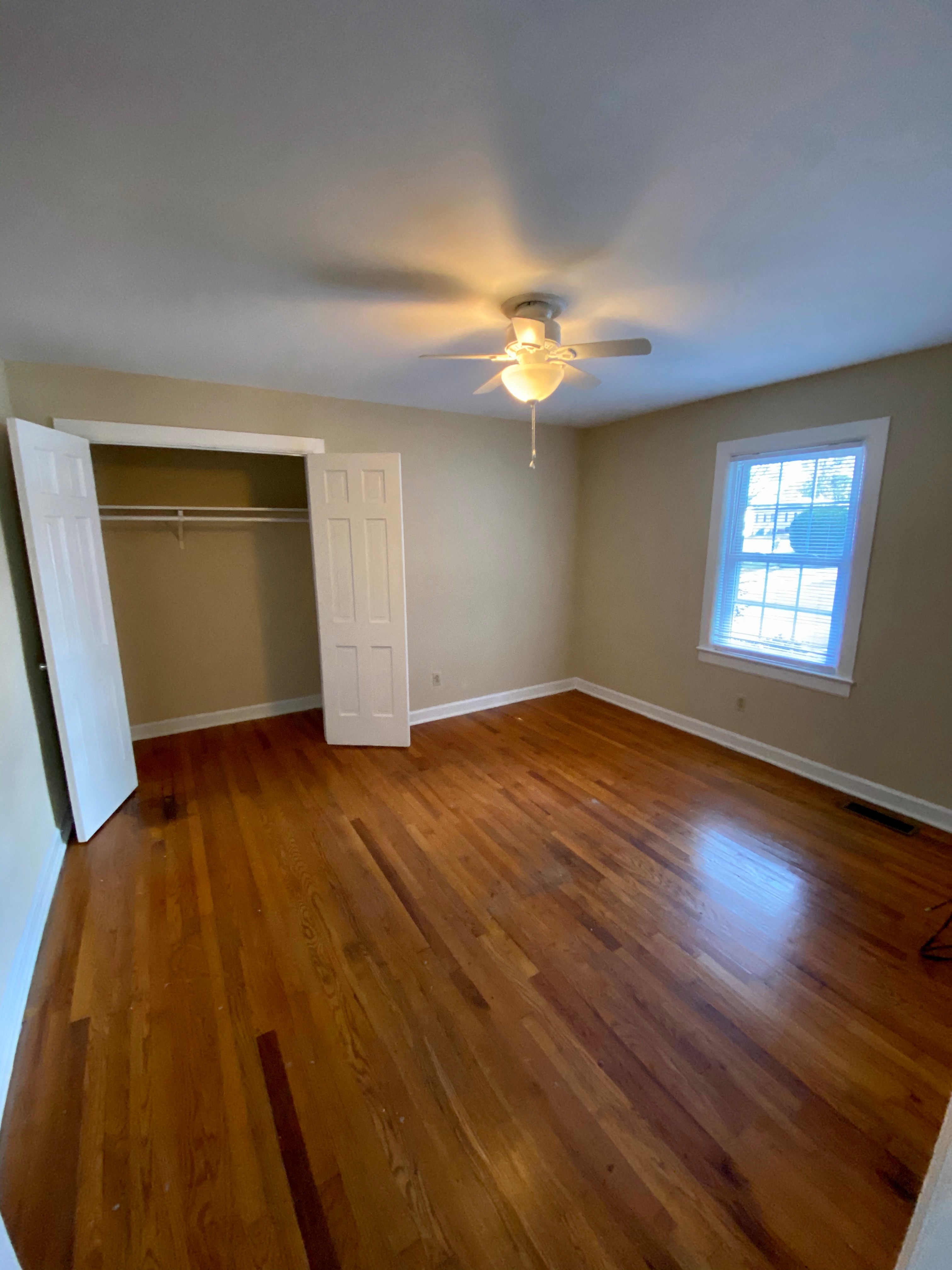 an empty living room with wooden floors and a ceiling fan