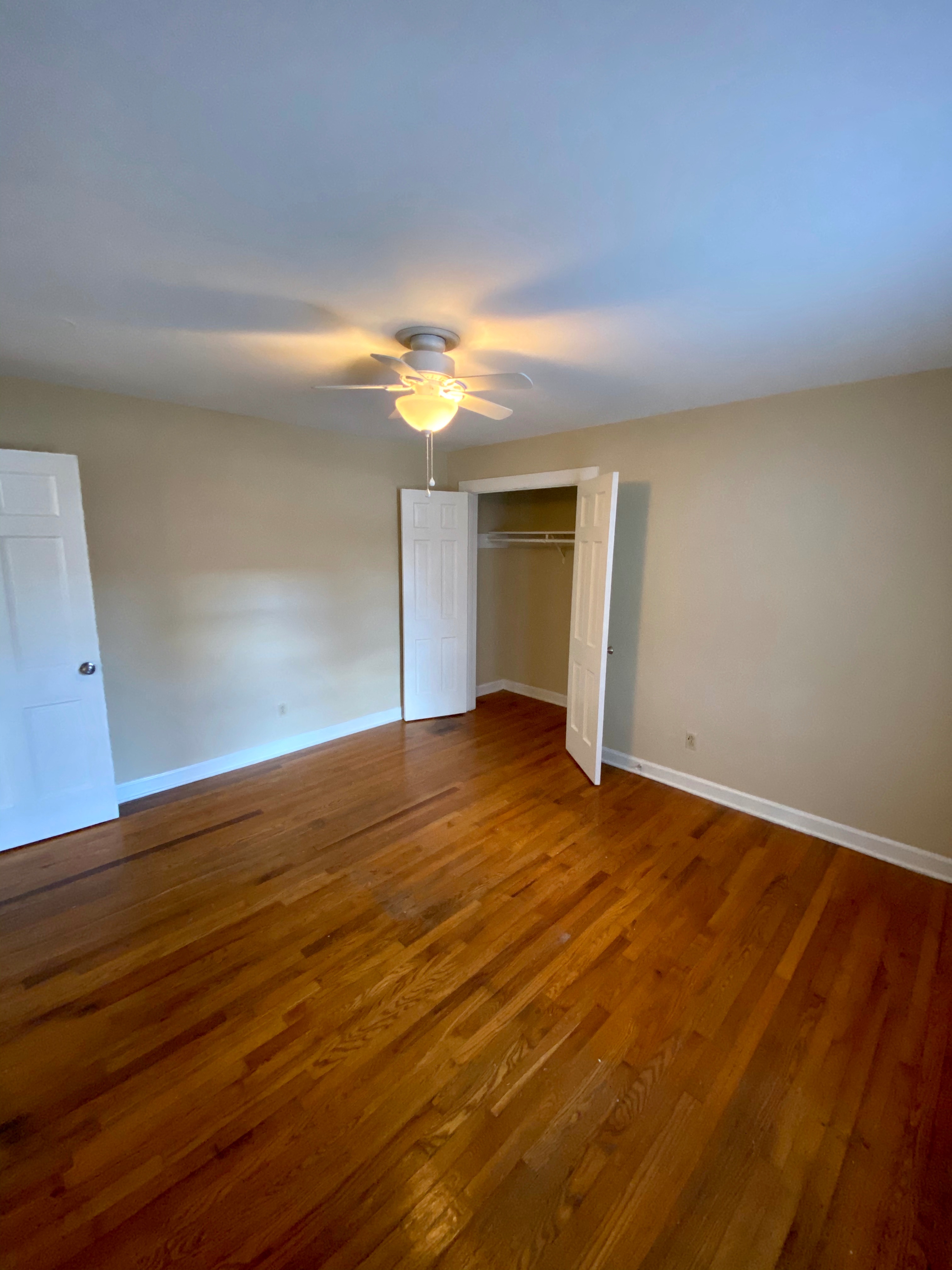 an empty living room with wood floors and a ceiling fan