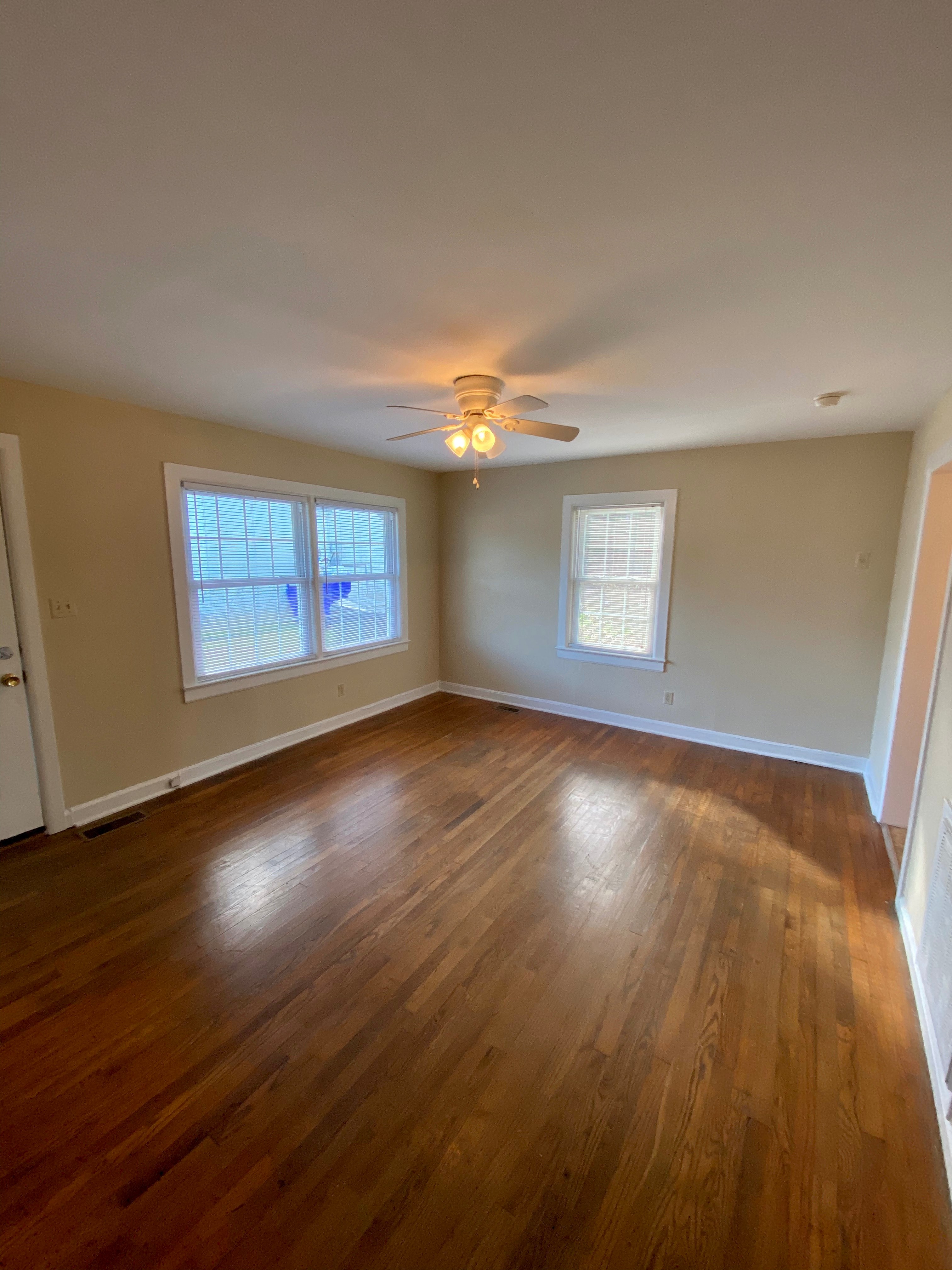 an empty living room with wood floors and a ceiling fan
