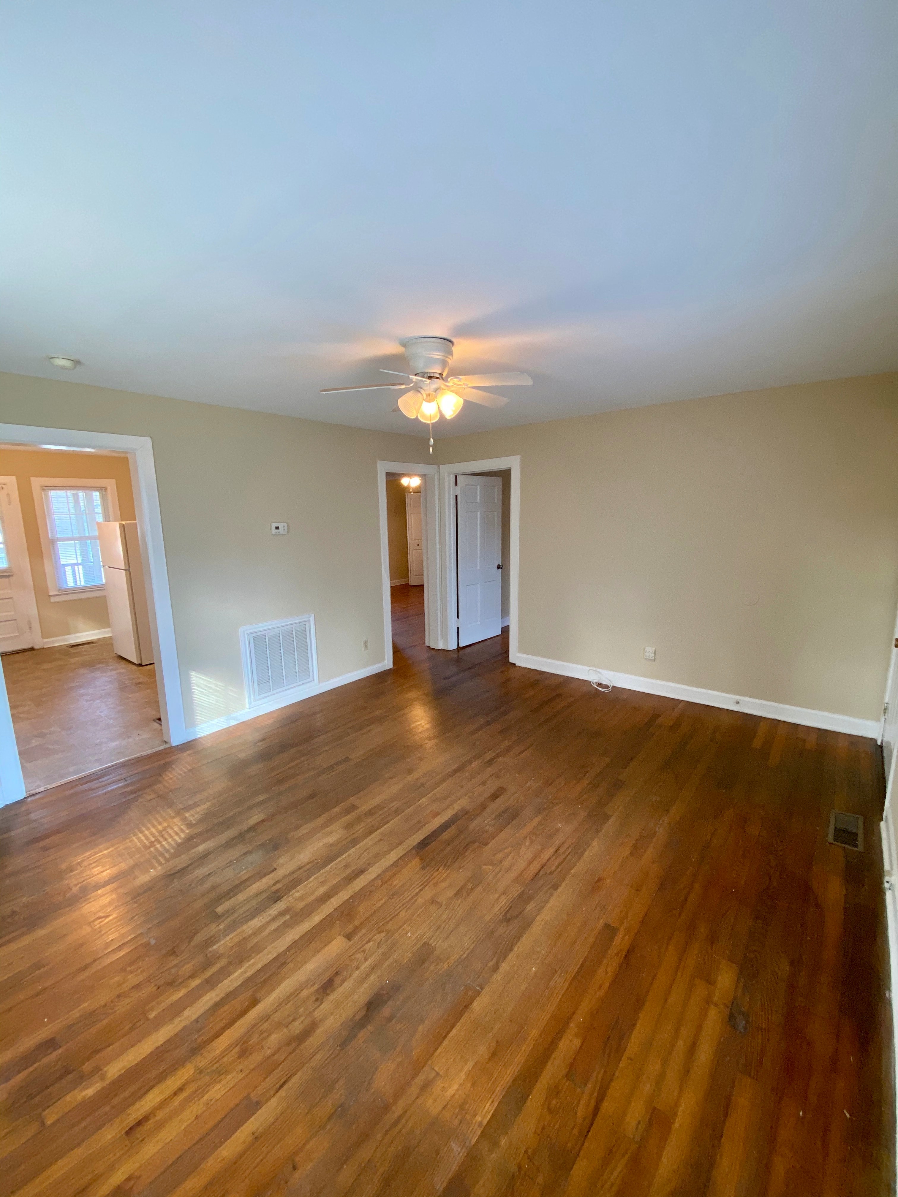 an empty living room with wooden floors and a ceiling fan