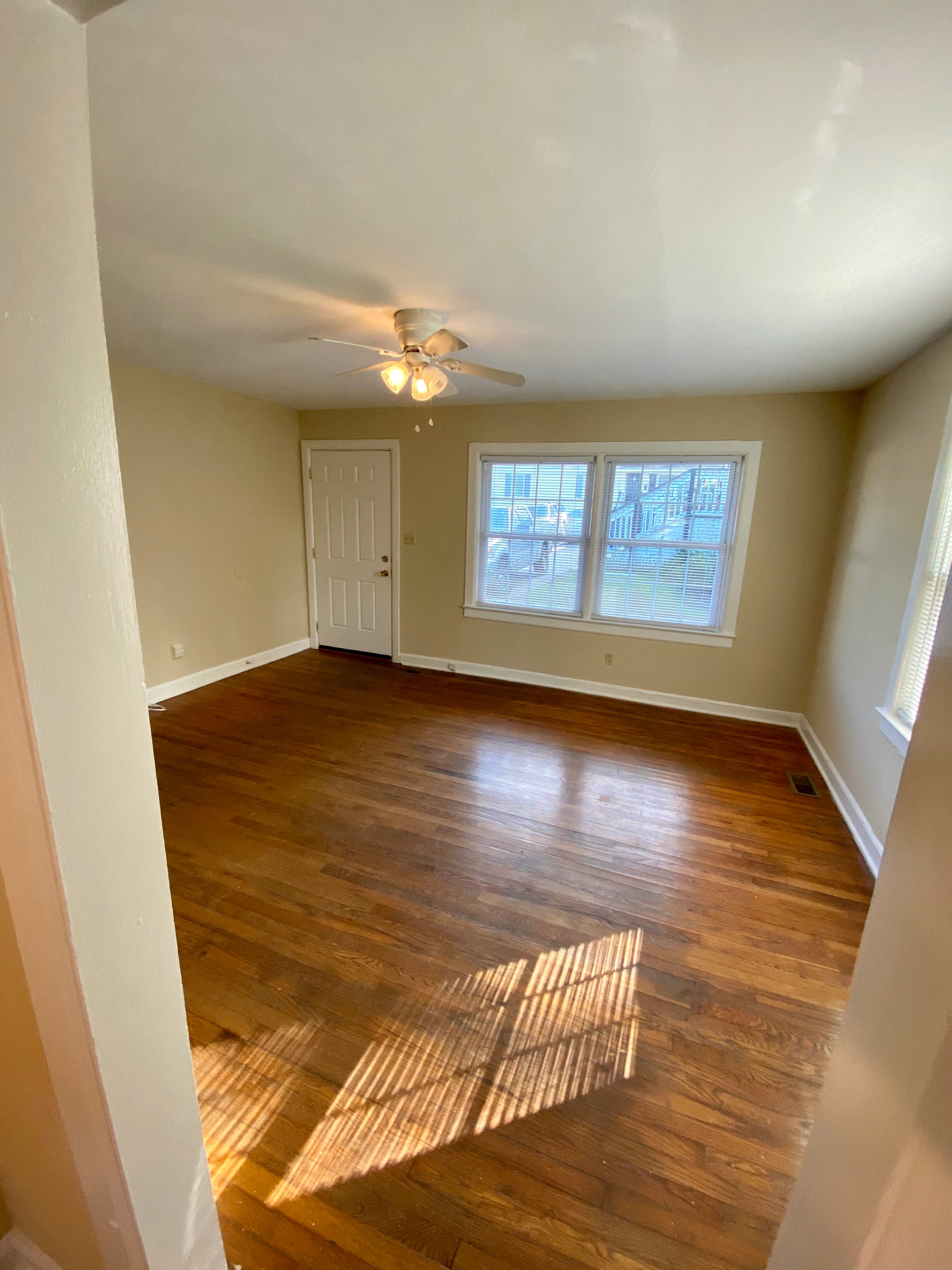 an empty living room with wooden floors and a ceiling fan
