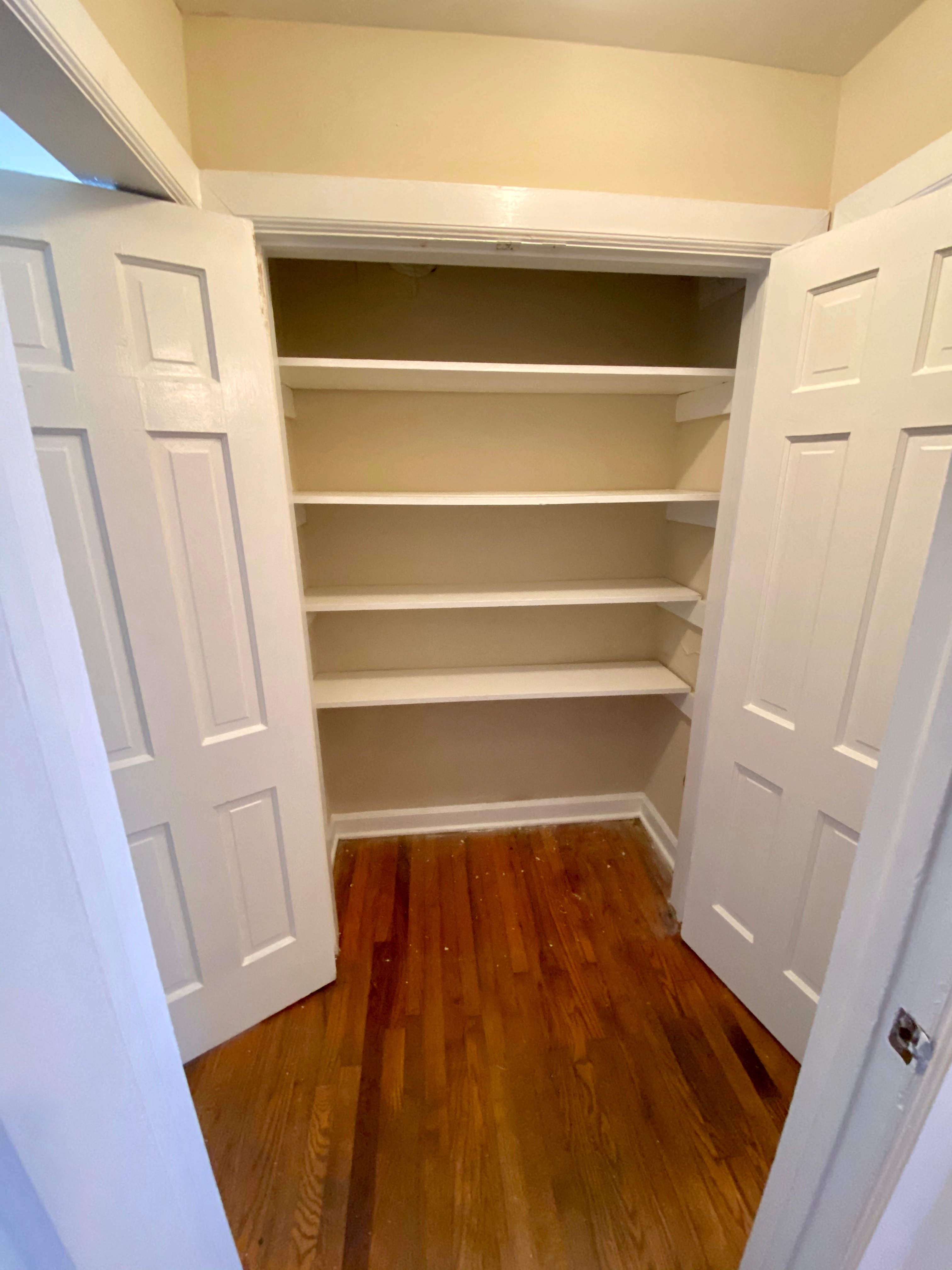 a small closet with shelves and a wooden floor