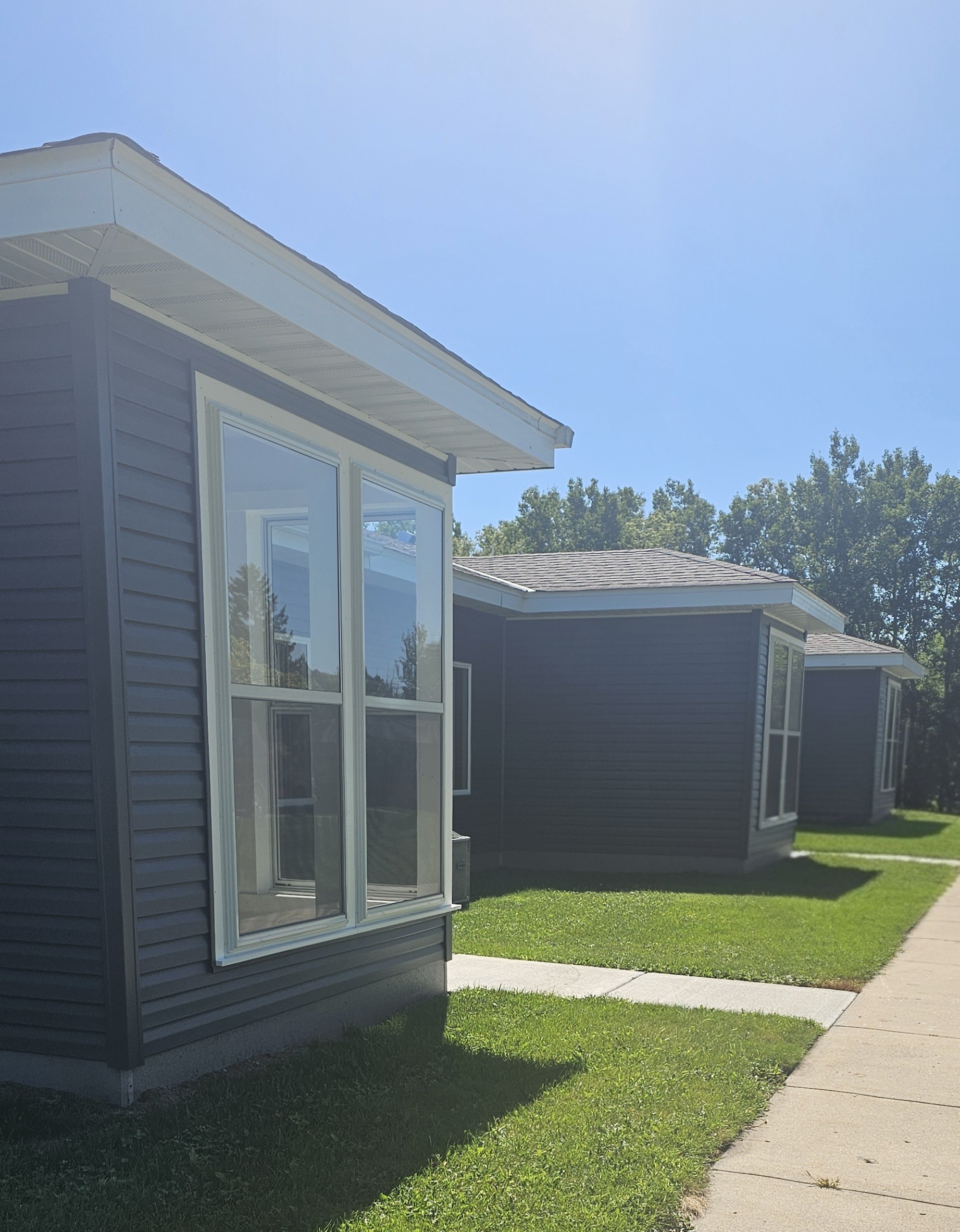 A small house with a grey siding and a white window.