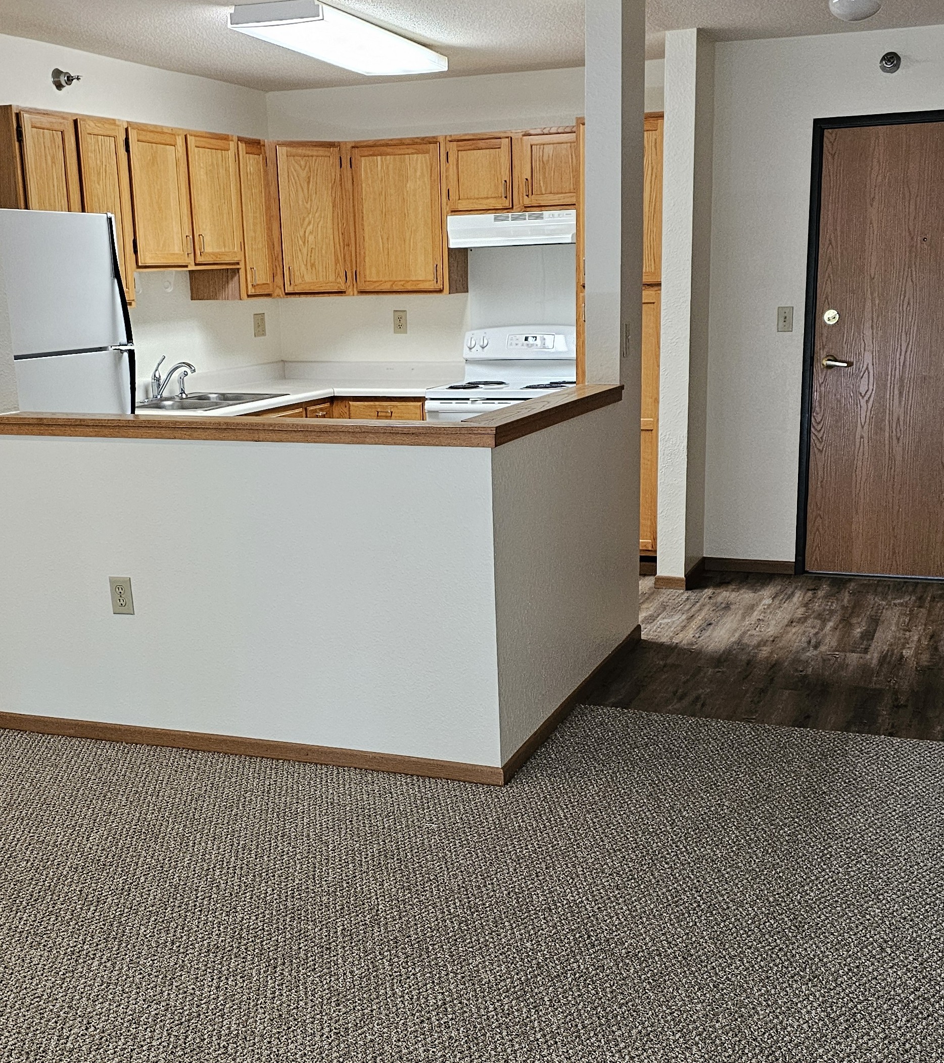 A kitchen with white countertops and wooden cabinets.