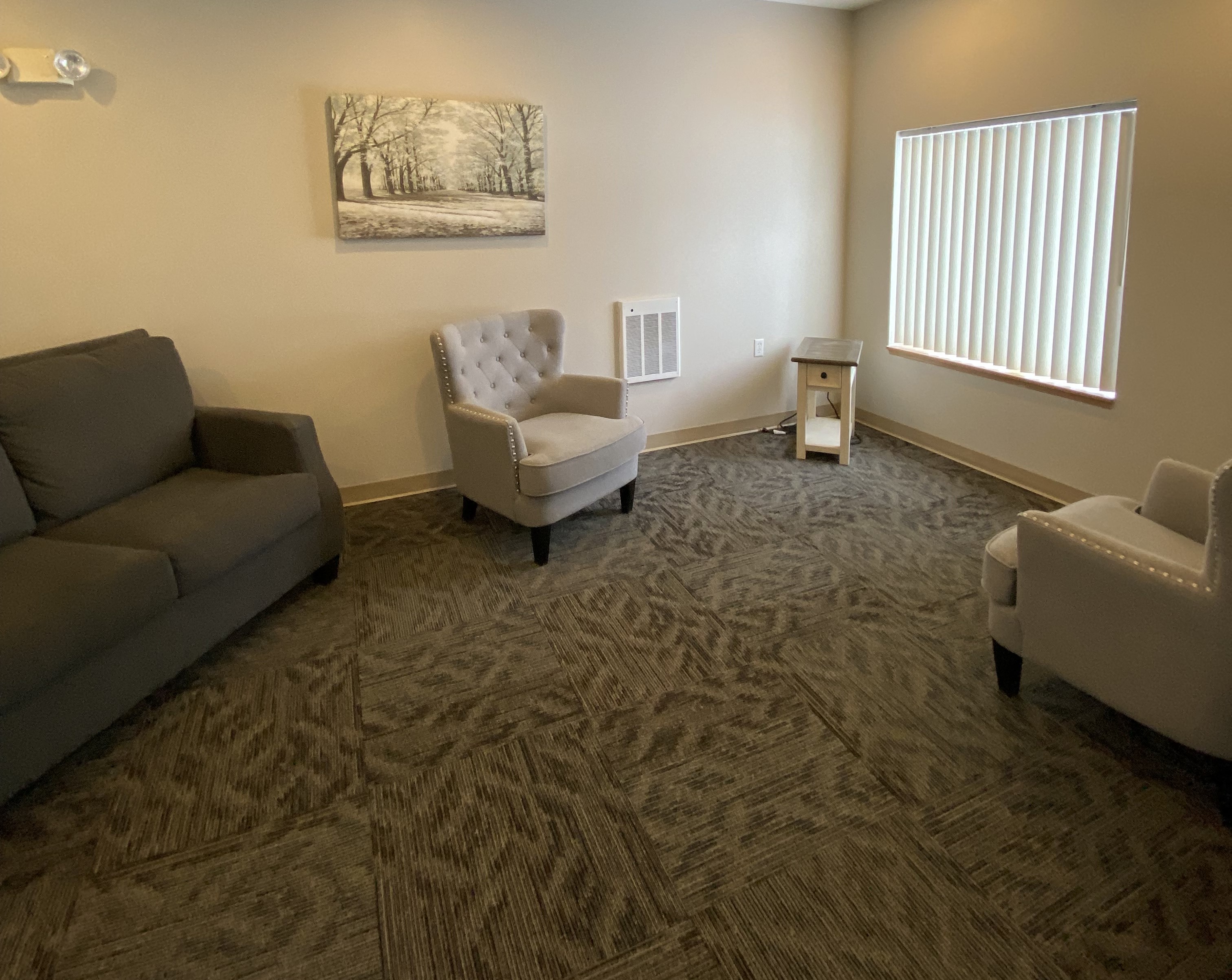 A living room with a grey couch, a white chair, and a small table.