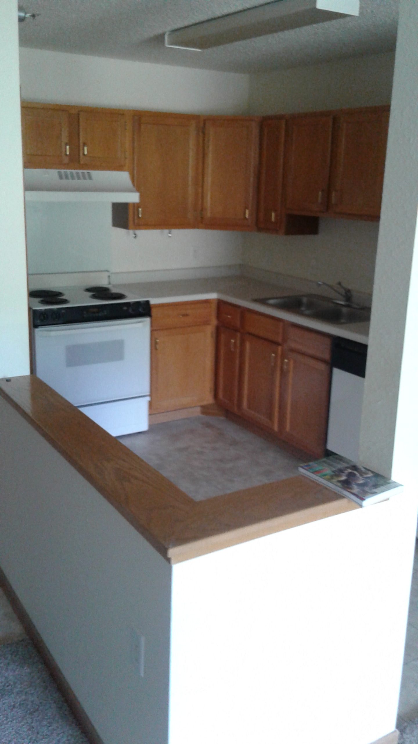 an empty kitchen with wooden cabinets and a white stove