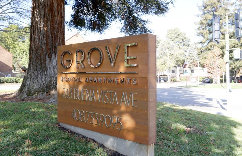 a sign for grove regional apartments in front of a tree