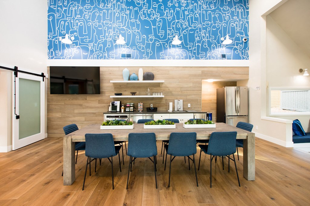 a dining room table with blue chairs in front of a kitchen
