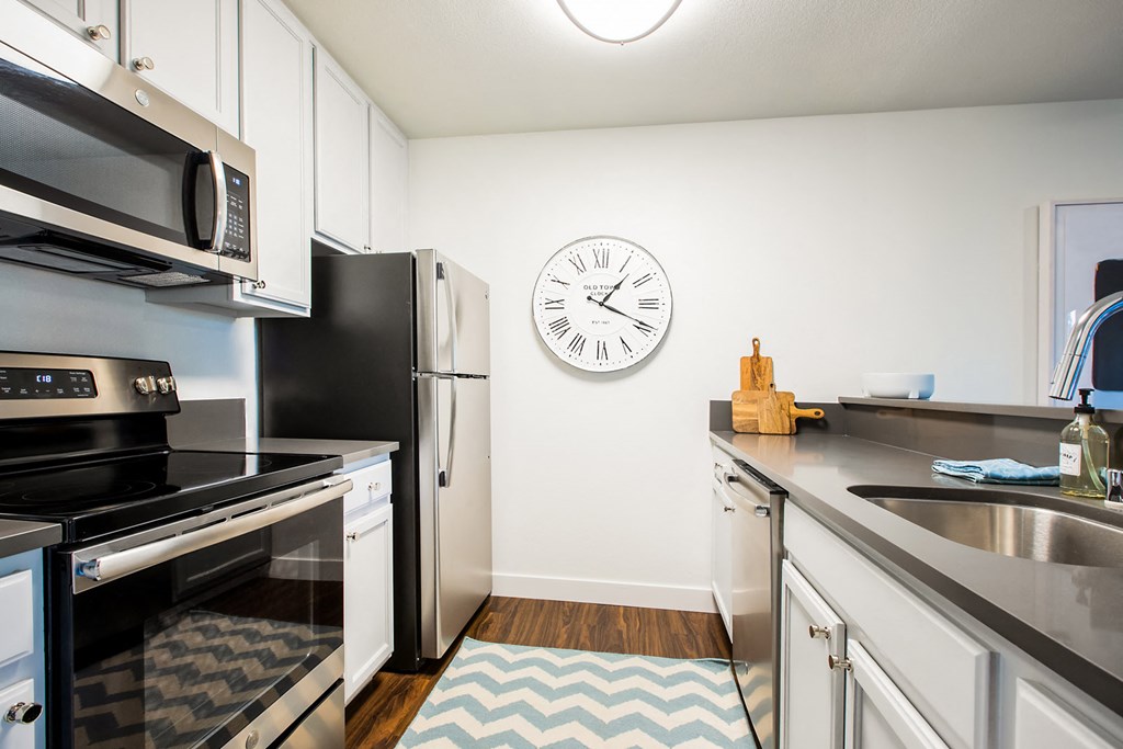 a kitchen with stainless steel appliances and a clock on the wall