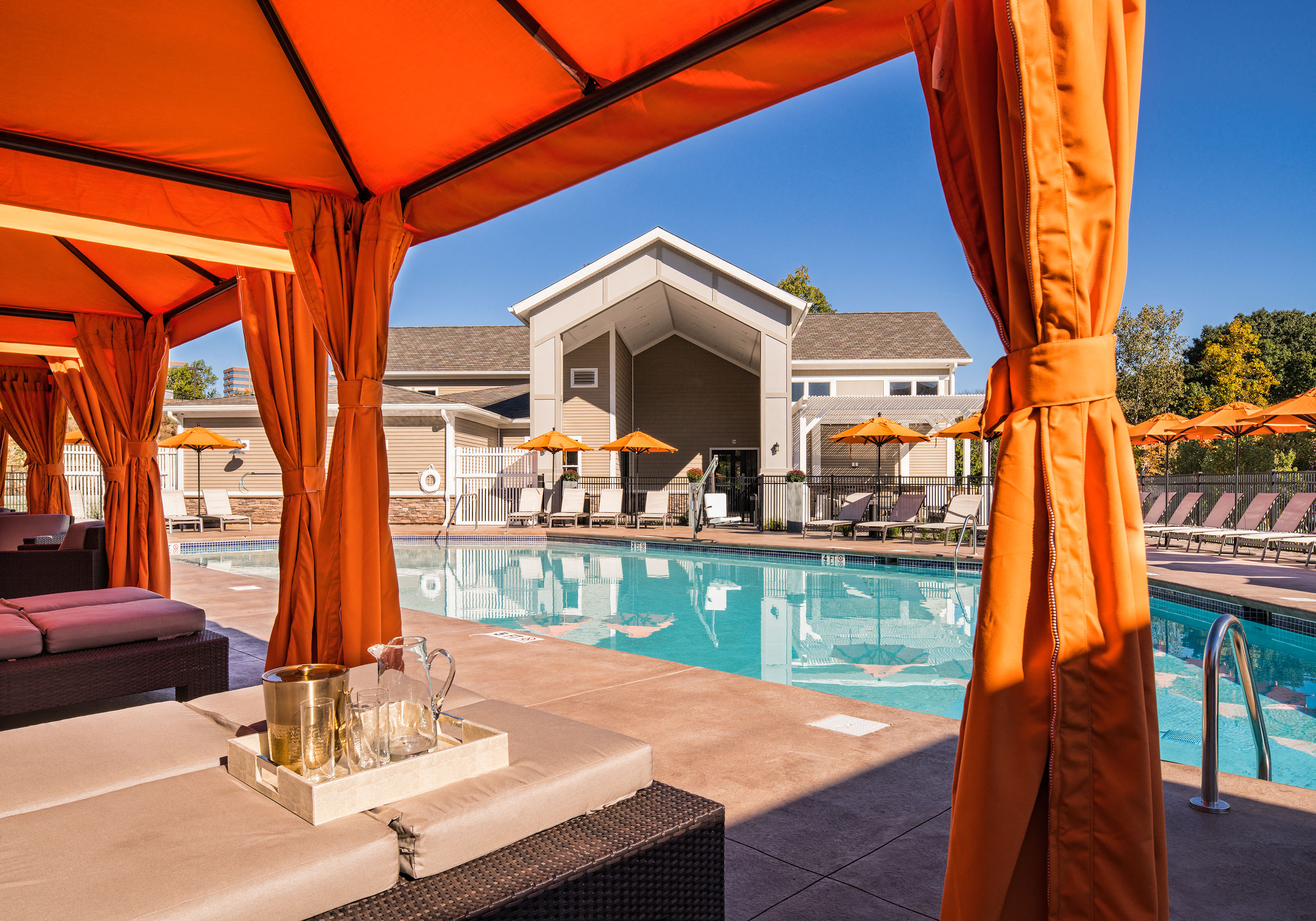 a swimming pool with orange umbrellas and a poolside lounge area with chairs