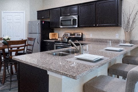 A kitchen with a granite countertop and black cabinets.