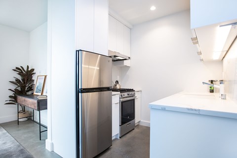 A modern kitchen with a stainless steel refrigerator and a white countertop.