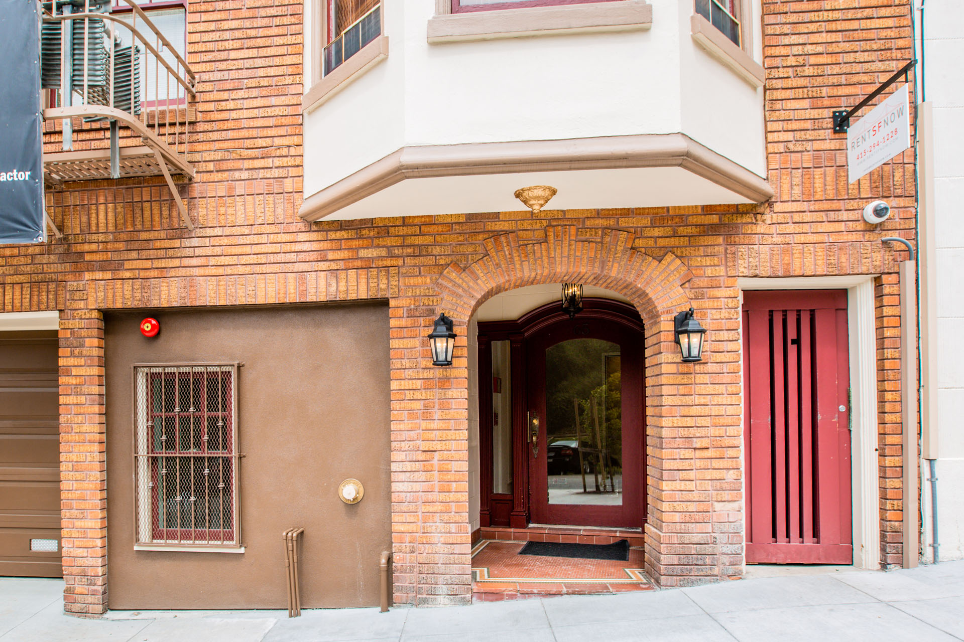 A red door is on the right side of a building.