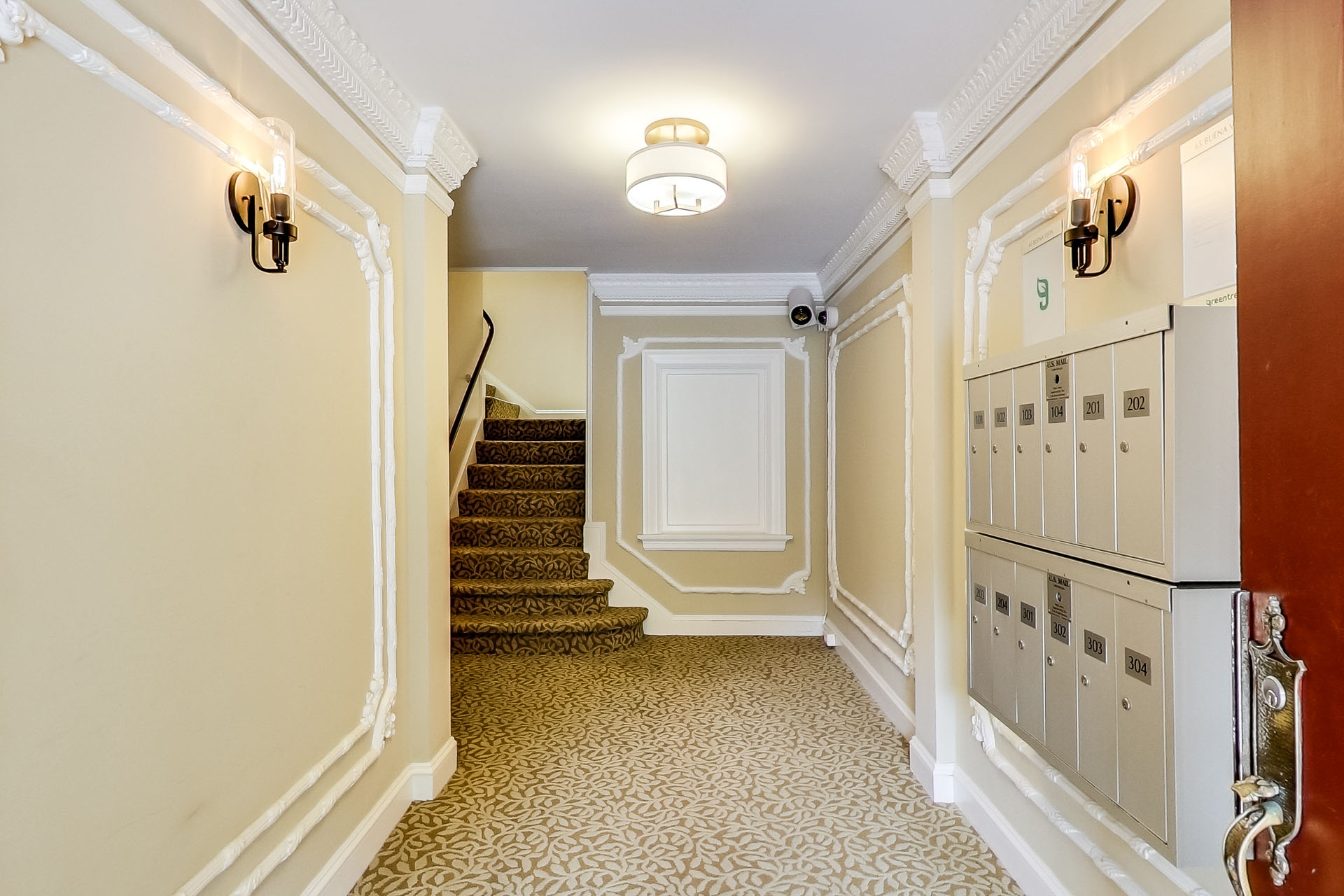 A hallway with a staircase and a red door.