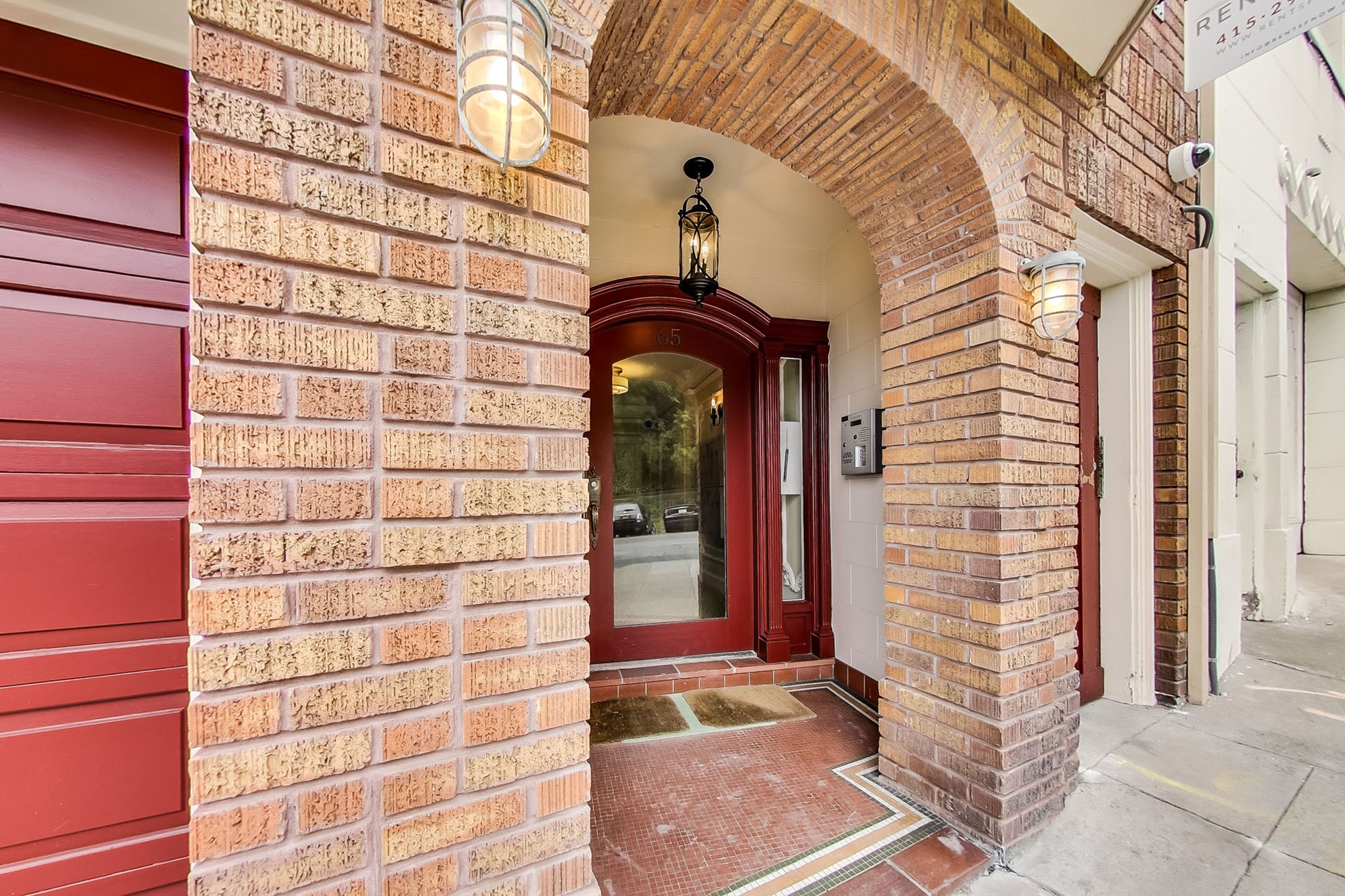 A red brick building with a white door and a sign that reads "RE1 11:27".