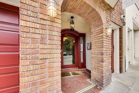A red brick building with a white door and a sign that reads "RE1 11:27".