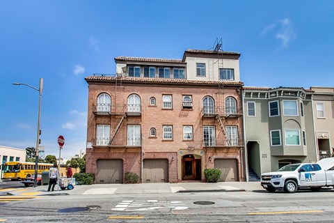 A red brick building with a white car parked in front of it.