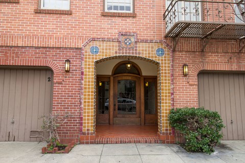 A red brick building with a wooden door and windows.