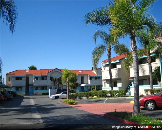 an apartment building with palm trees in a parking lot
