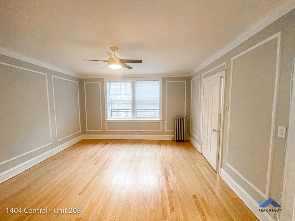 the living room of a home with wood floors and a ceiling fan