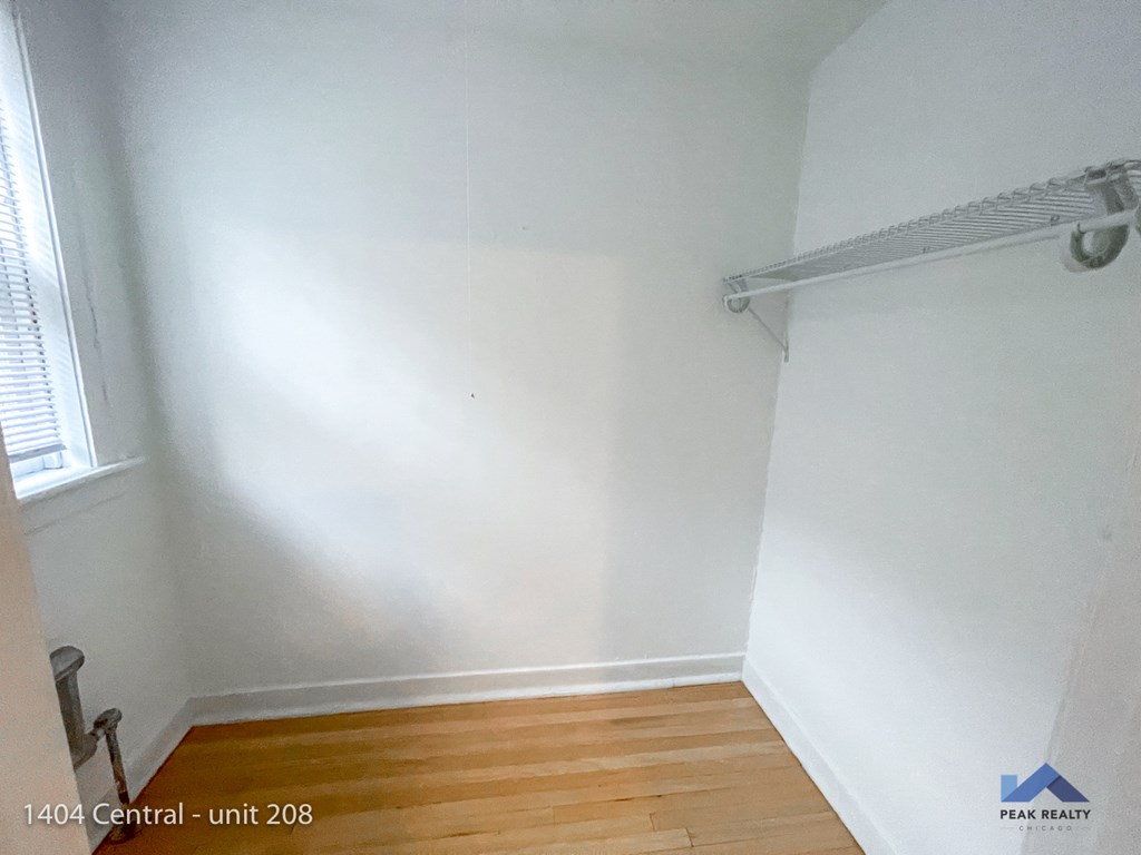 an empty room with white walls and a wooden floor and a window