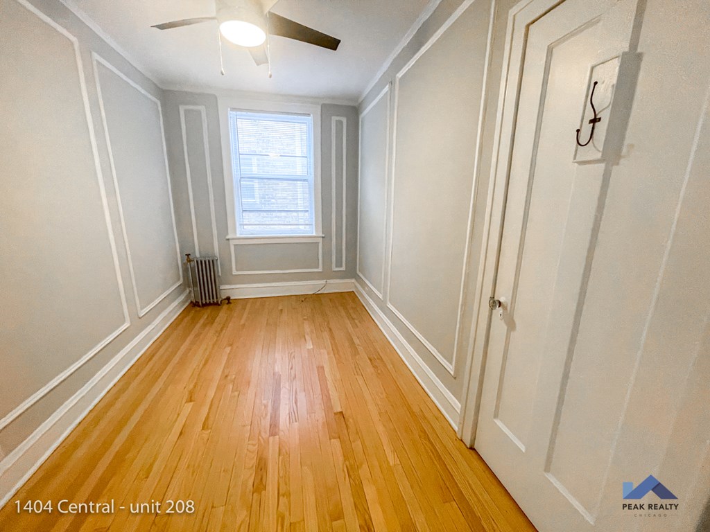 an empty room with wood floors and white walls and a window