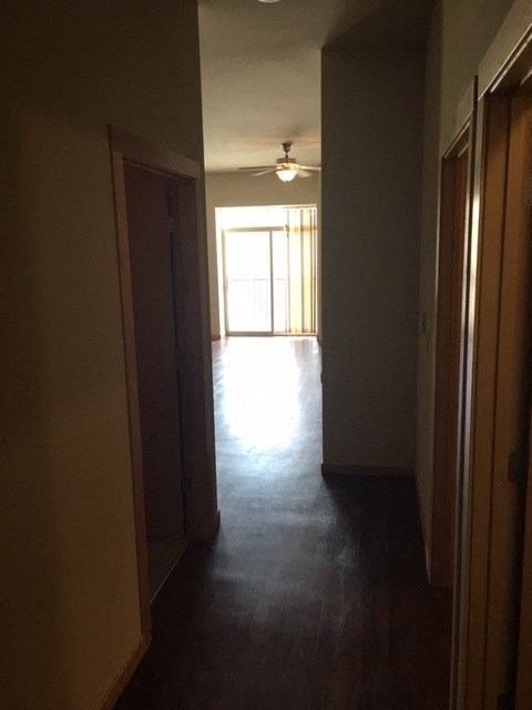 a hallway with a wood floor and a ceiling fan