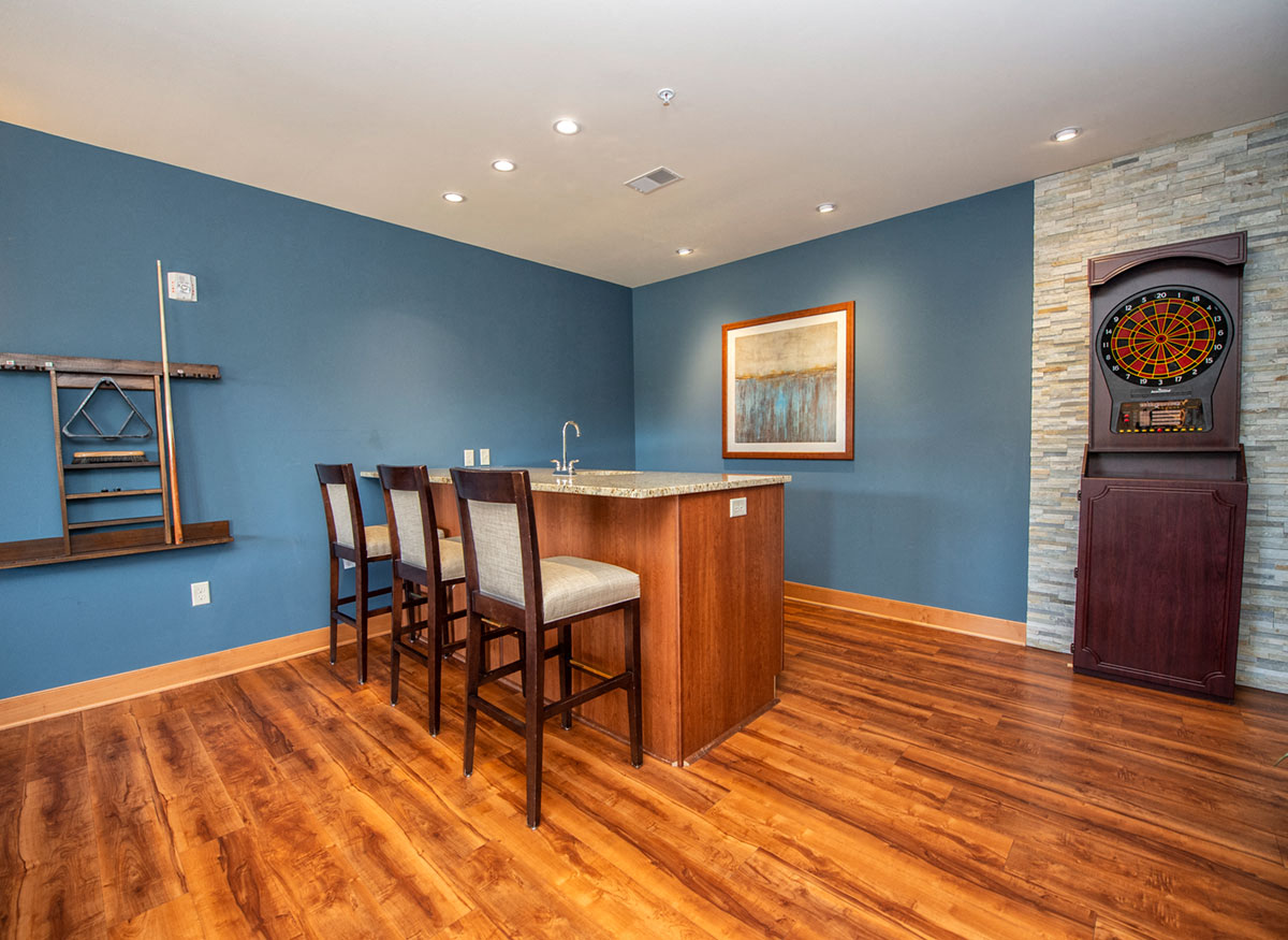 a living room with a bar and a blue wall and wood floors