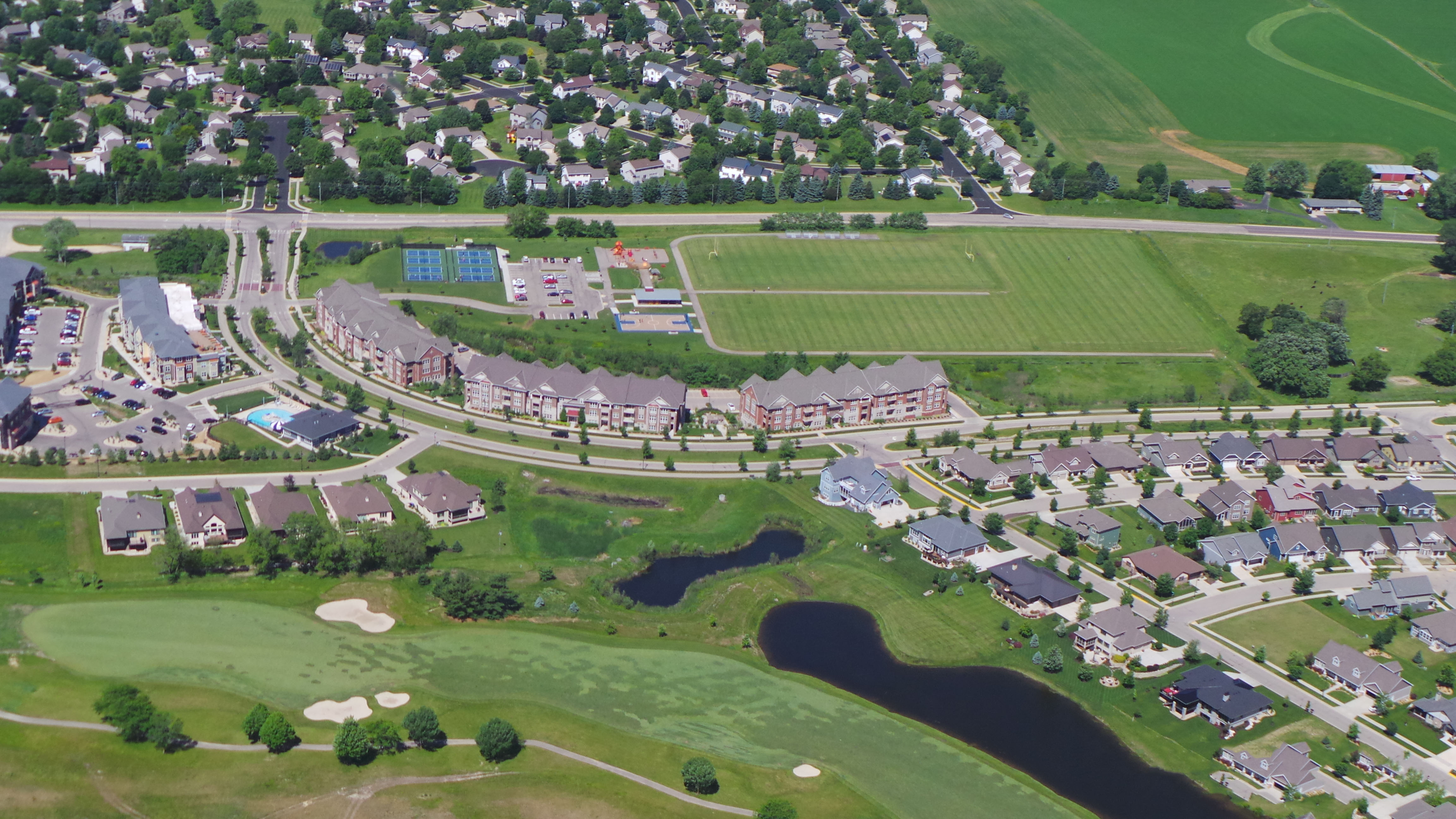 an aerial view of a suburban neighborhood with a golf course and a body of water
