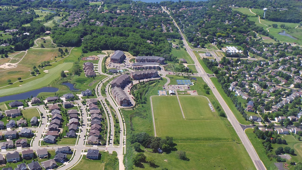 an aerial view of a suburban neighbourhood with a field and a park
