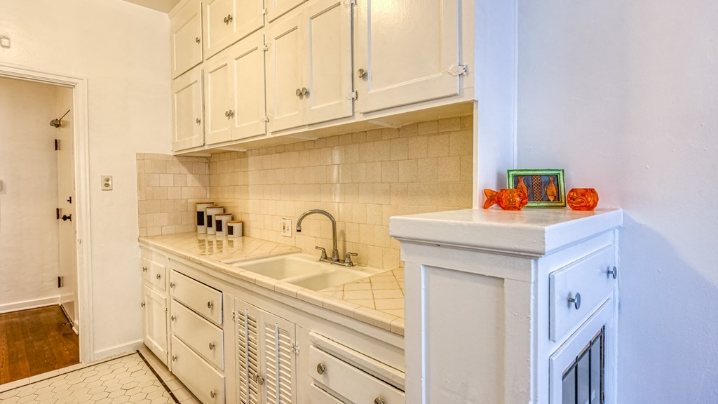 a white kitchen with white cabinets and a sink
