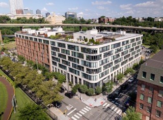 A large white building with a lot of windows is surrounded by trees.