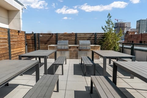an outdoor seating area with tables and benches on a rooftop