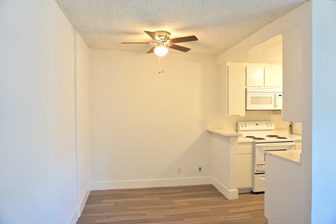 A small kitchen with a wood floor and a ceiling fan.