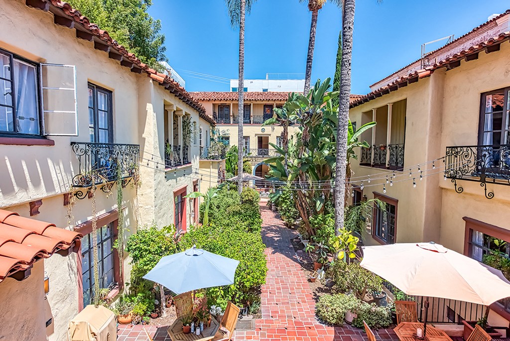 a courtyard with tables and umbrellas in front of a building