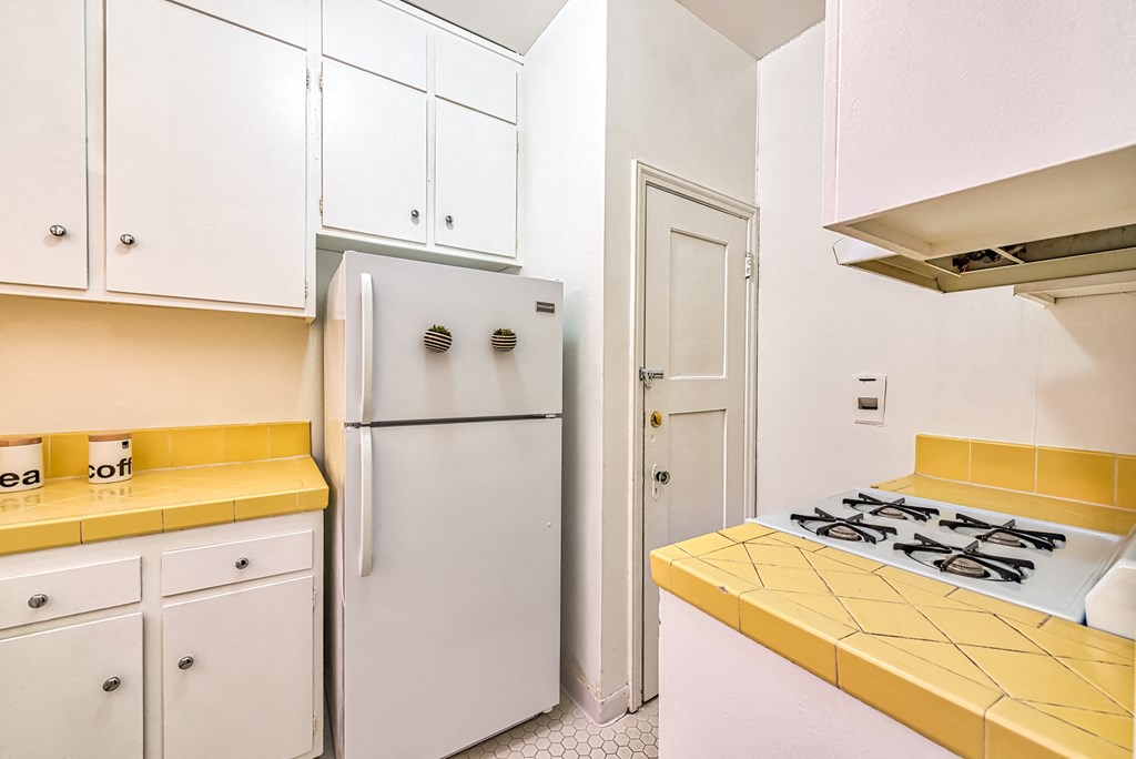 a kitchen with white cabinets and a yellow counter top and a refrigerator