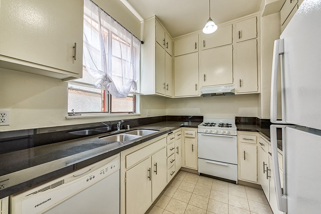 an empty kitchen with white appliances and white cabinets