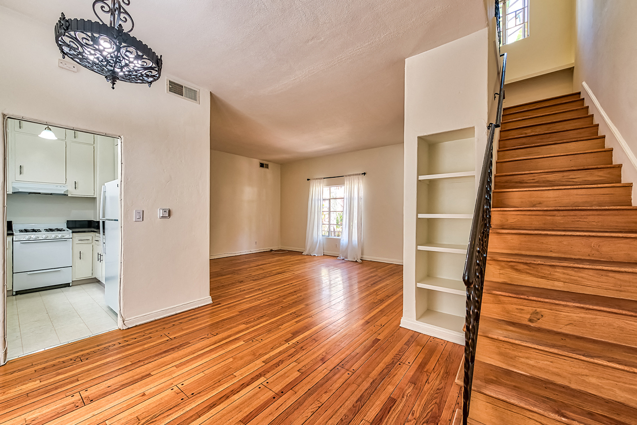 an empty living room with wood floors and a staircase
