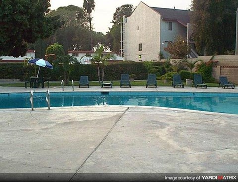 a swimming pool with four chairs and an umbrella