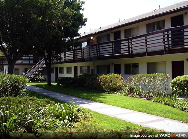 an apartment building with a sidewalk and trees