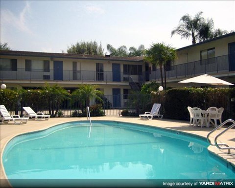 a large swimming pool with chairs and a umbrella