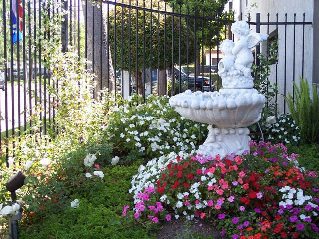 a fountain in the middle of a garden of flowers