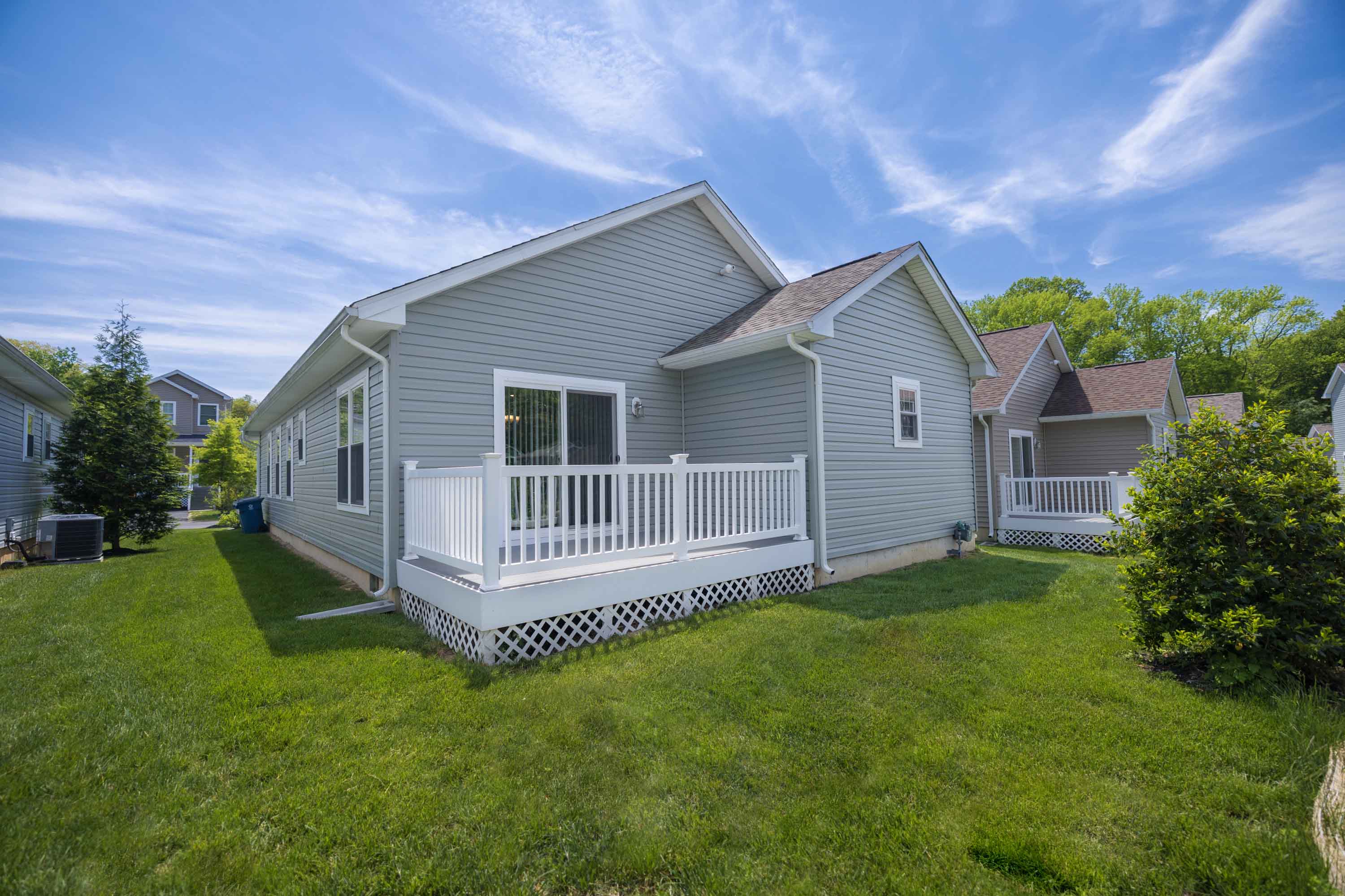 a gray house with a white porch and a yard