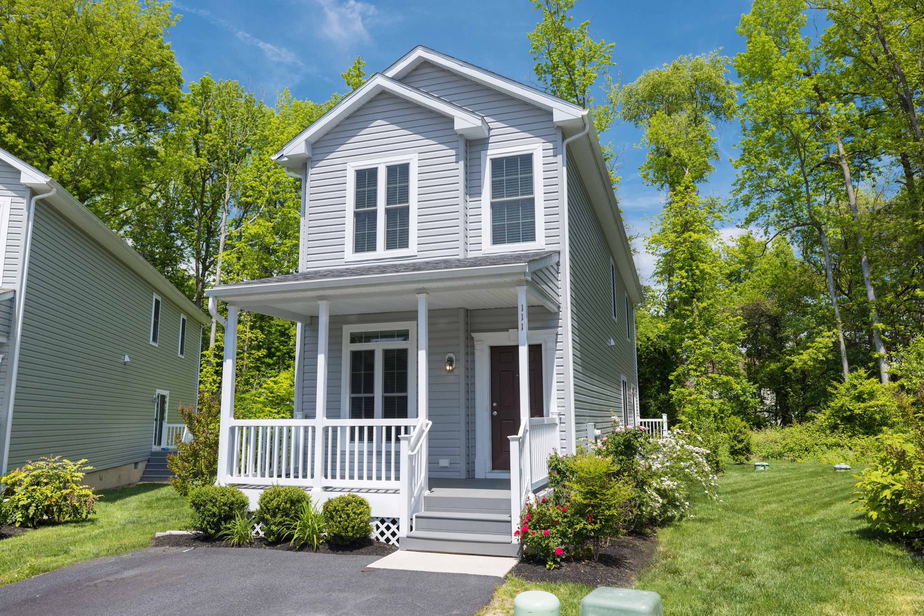 the front of a gray house with a white porch
