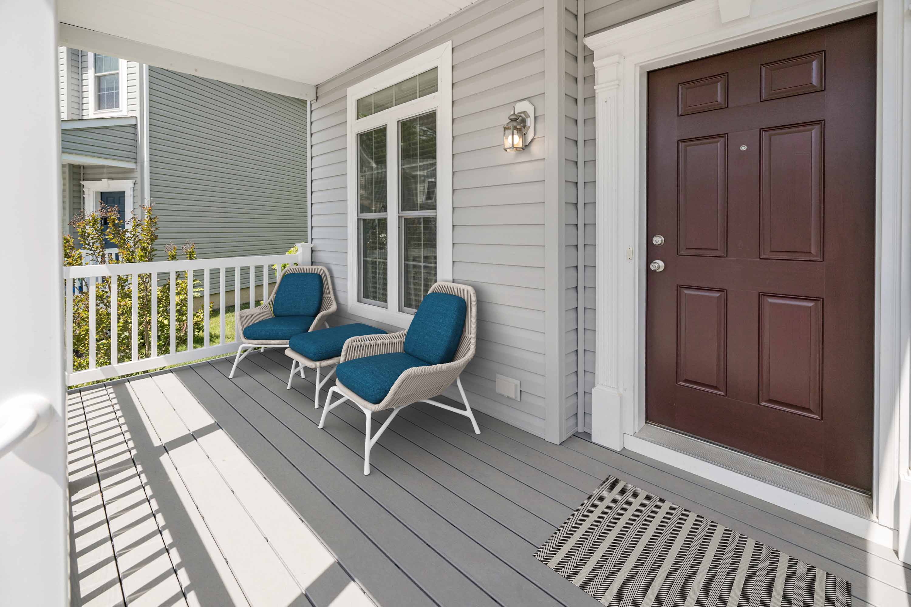 a front porch with two chairs and a brown door