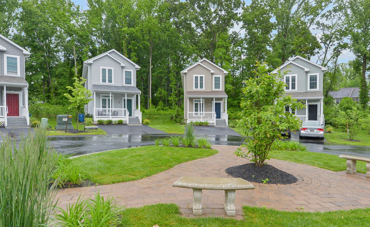 a group of houses on a street with a sidewalk and a bench