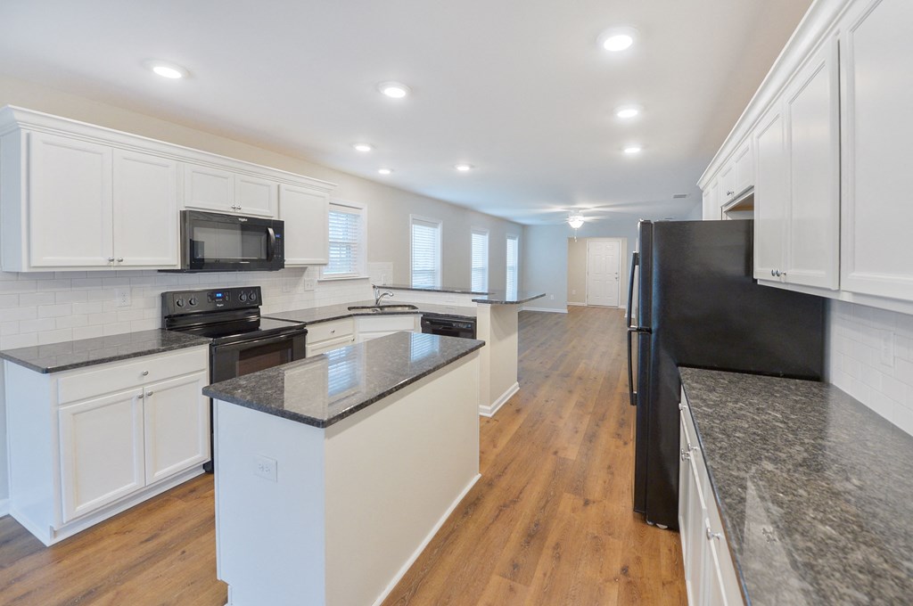 a large kitchen with white cabinets and black appliances